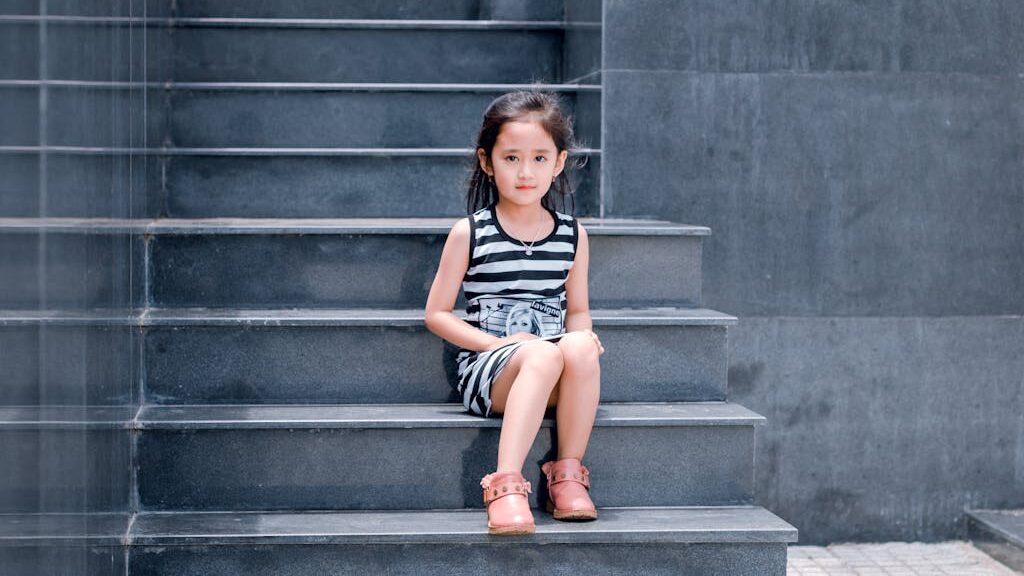 Girl Wearing Black and White Striped Dress Sitting on Stair